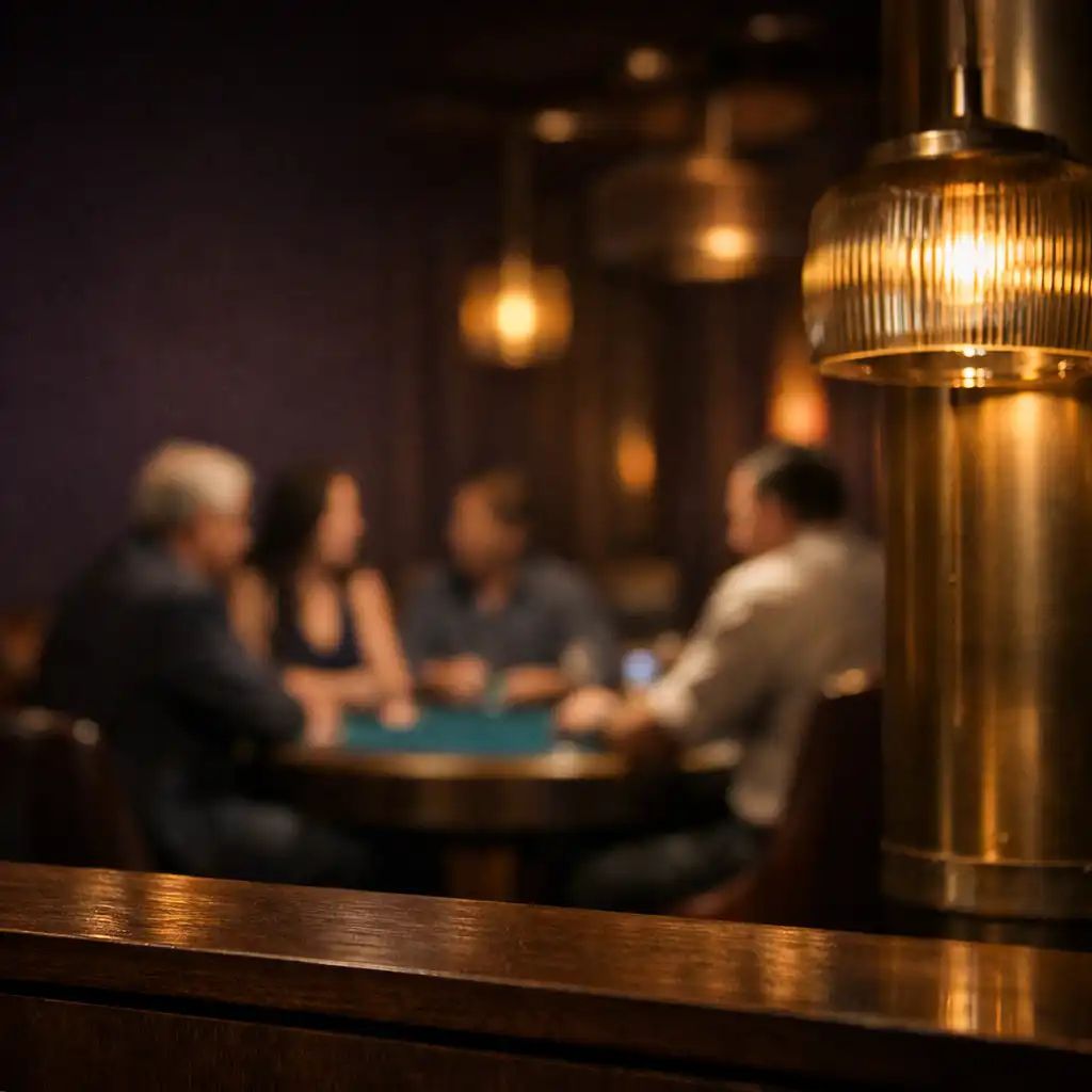 Warm pendant light and dark timber framing guests at a teal-felt poker table in Cardemble’s lounge